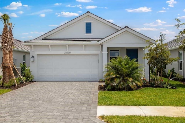 26930 Lark Ct, Punta Gorda, FL 33955 - ranch-style house featuring stucco siding, decorative driveway, a garage, and a front yard