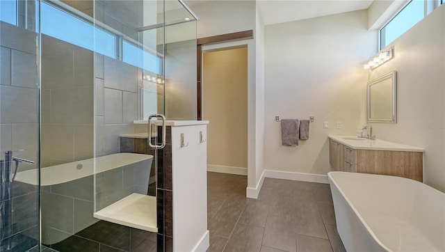 bathroom featuring a stall shower, baseboards, a soaking tub, tile patterned flooring, and vanity