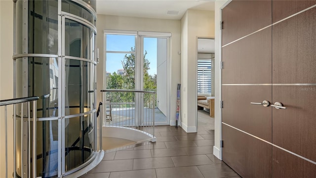 doorway featuring baseboards, visible vents, and dark tile patterned flooring