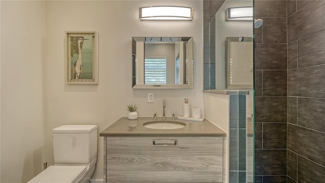 bathroom featuring a tile shower, vanity, and toilet