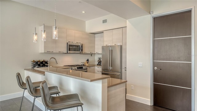 kitchen featuring a peninsula, a breakfast bar, visible vents, hanging light fixtures, and appliances with stainless steel finishes