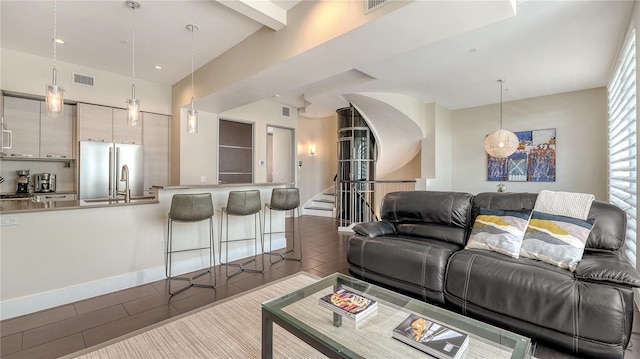 living area with visible vents, wood tiled floor, stairway, and baseboards