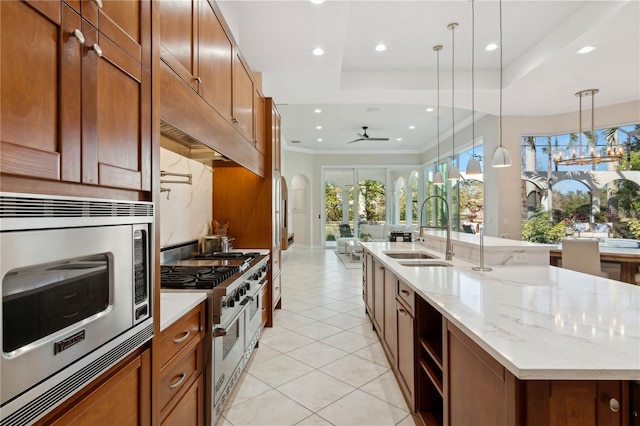 13315 Palmers Creek Ter, Lakewood Ranch, FL 34202 - kitchen with sink, light stone counters, an island with sink, pendant lighting, and stainless steel appliances