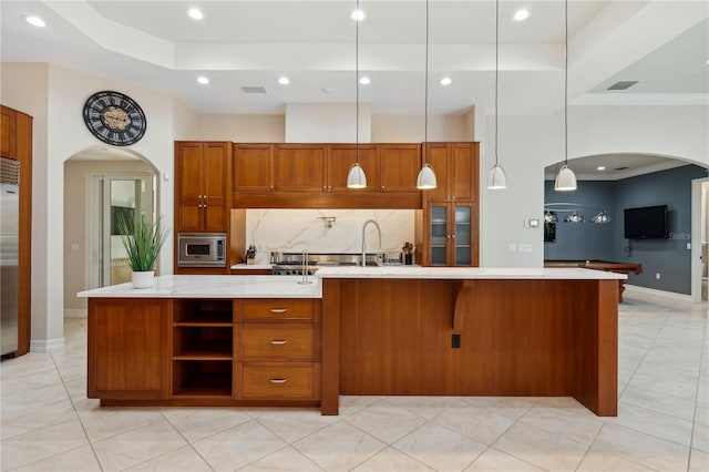 13315 Palmers Creek Ter, Lakewood Ranch, FL 34202 - kitchen featuring a large island, built in appliances, tasteful backsplash, light stone countertops, and decorative light fixtures