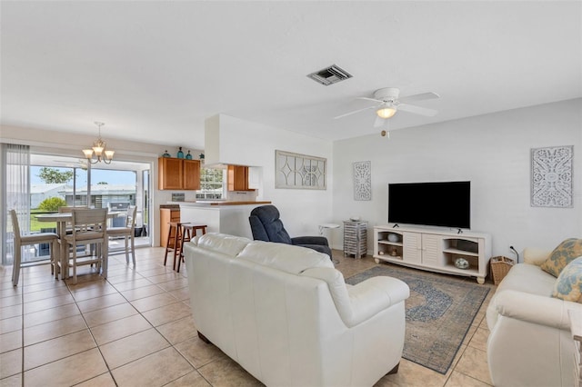 tiled living room featuring ceiling fan with notable chandelier