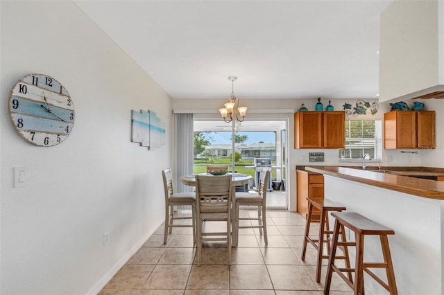 kitchen with pendant lighting, an inviting chandelier, a breakfast bar area, and light tile patterned floors