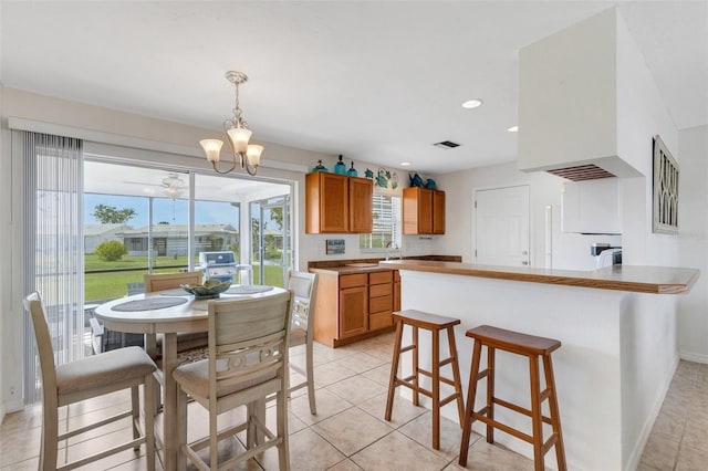 kitchen with pendant lighting, a breakfast bar, an inviting chandelier, and light tile patterned floors