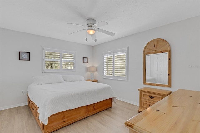 bedroom featuring ceiling fan, multiple windows, and light hardwood / wood-style flooring