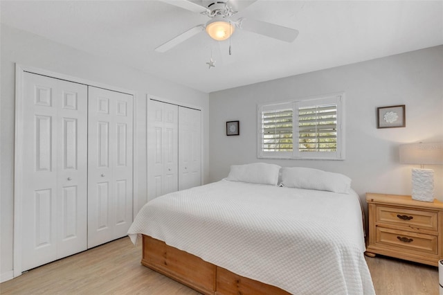 bedroom featuring multiple closets, ceiling fan, and light hardwood / wood-style floors