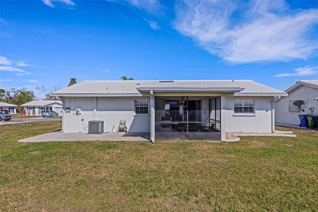 rear view of property with a patio, a sunroom, a yard, and central AC