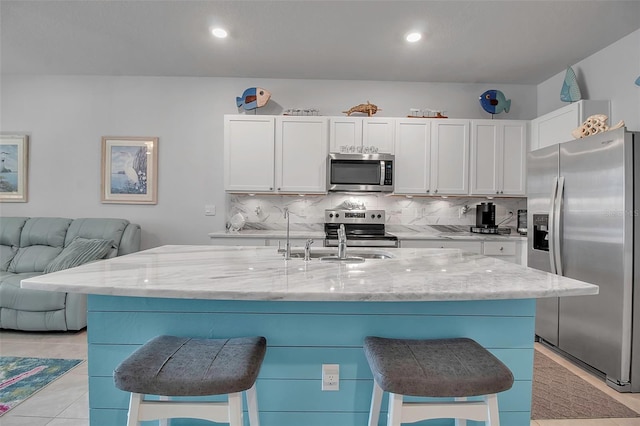 kitchen with appliances with stainless steel finishes, a kitchen bar, and a center island with sink