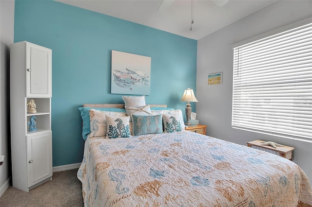 carpeted bedroom featuring multiple windows and ceiling fan