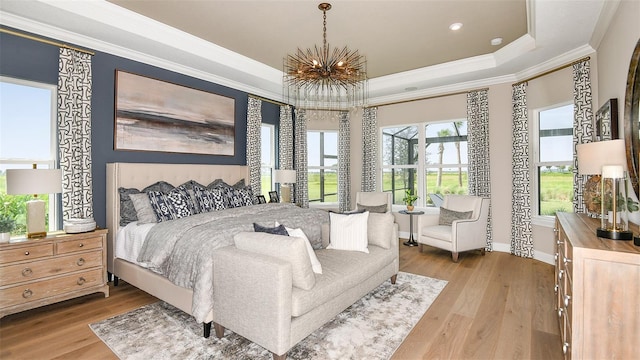 bedroom featuring wood-type flooring, an inviting chandelier, crown molding, and a tray ceiling