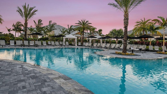 pool at dusk featuring a patio