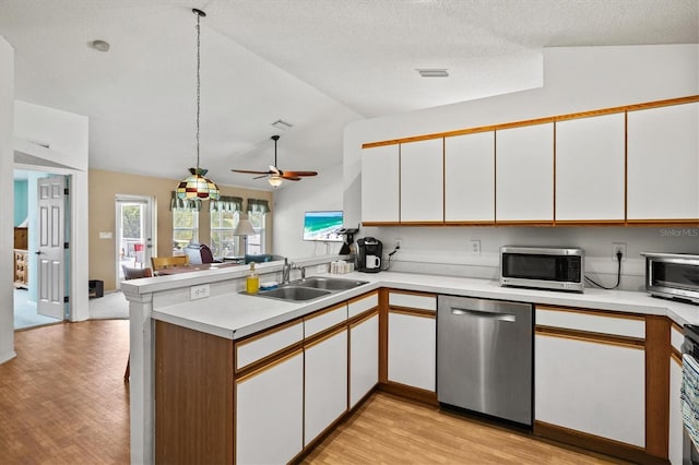 kitchen featuring sink, white cabinetry, appliances with stainless steel finishes, kitchen peninsula, and pendant lighting