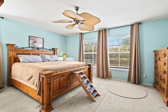 carpeted bedroom with ceiling fan and a textured ceiling