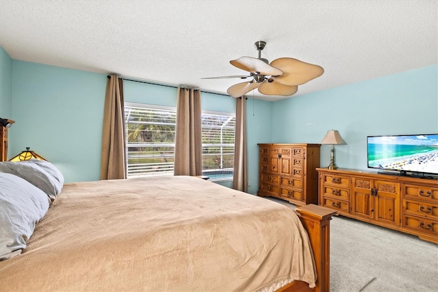 bedroom with ceiling fan, light carpet, and a textured ceiling