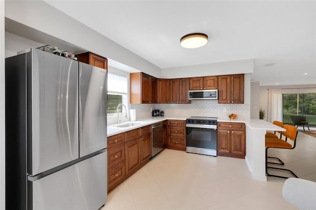 kitchen featuring a sink, stainless steel appliances, decorative backsplash, and light countertops