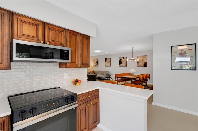 kitchen with electric range, stainless steel microwave, backsplash, a peninsula, and brown cabinetry