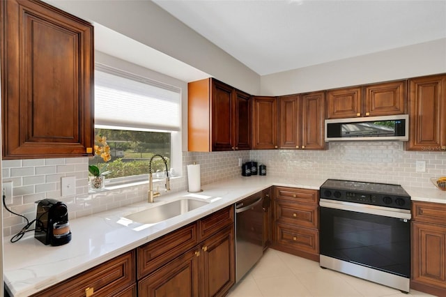 kitchen with a sink, decorative backsplash, appliances with stainless steel finishes, and light tile patterned floors