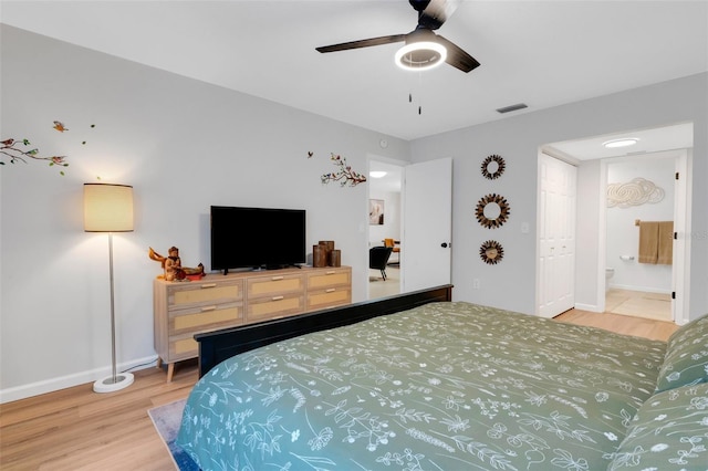 bedroom featuring visible vents, baseboards, wood finished floors, and ensuite bathroom