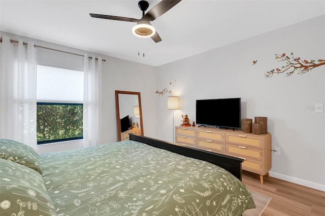 bedroom with light wood finished floors, ceiling fan, and baseboards