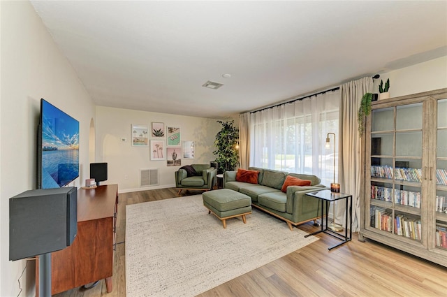 living room with baseboards, visible vents, and light wood finished floors