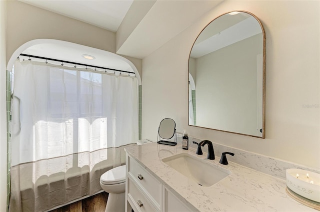 full bath featuring toilet, curtained shower, wood finished floors, and vanity