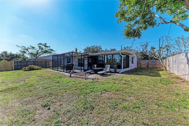 back of property with a lawn, a fenced backyard, and a lanai