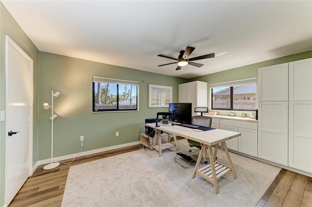 home office featuring baseboards, light wood finished floors, and a healthy amount of sunlight