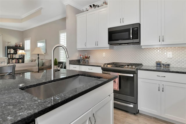 kitchen featuring white cabinetry, stainless steel appliances, and dark stone countertops