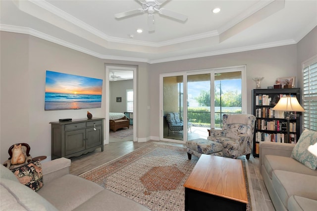 living room with a raised ceiling, a wealth of natural light, and light hardwood / wood-style flooring