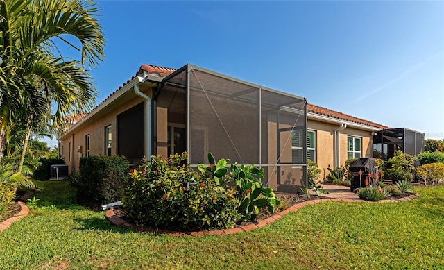 view of home's exterior with a yard and glass enclosure