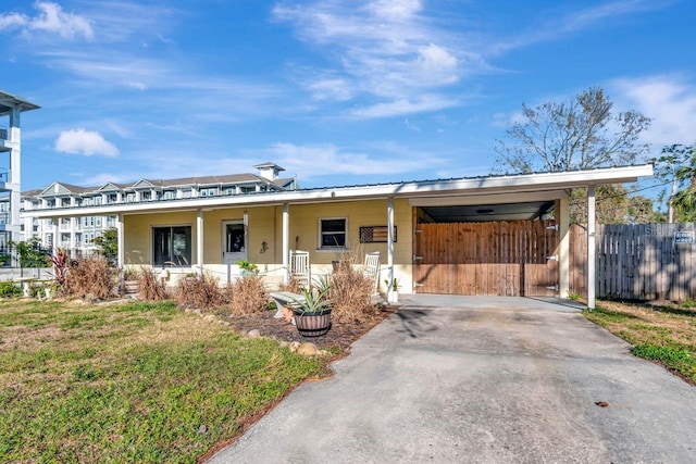 view of front of house with a carport, a front yard, fence, and driveway