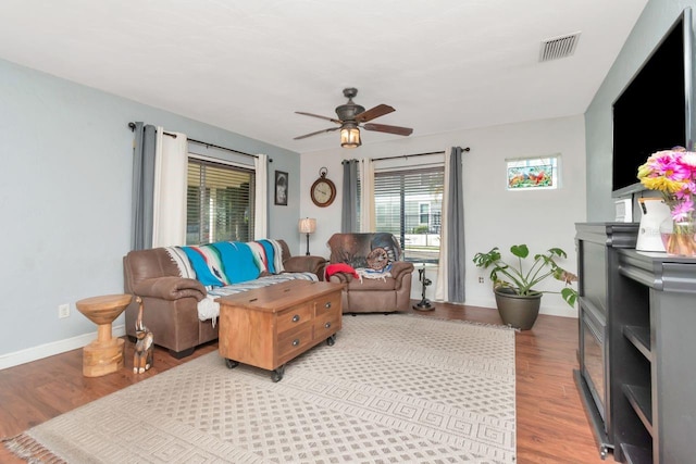 living room featuring light wood-style floors, ceiling fan, visible vents, and baseboards