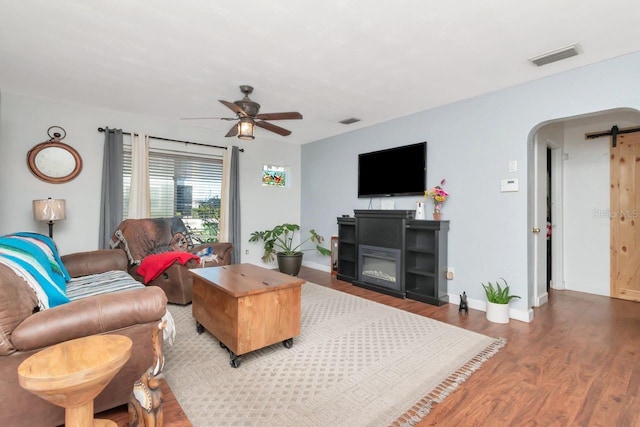 living area with baseboards, visible vents, arched walkways, ceiling fan, and wood finished floors