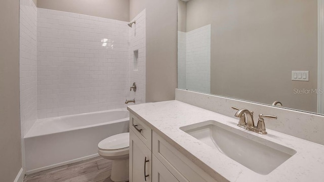 full bathroom with tiled shower / bath combo, vanity, hardwood / wood-style flooring, and toilet