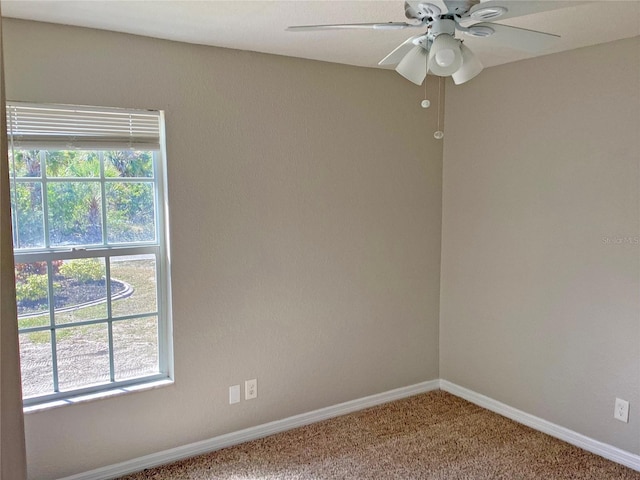 carpeted spare room featuring a wealth of natural light and ceiling fan