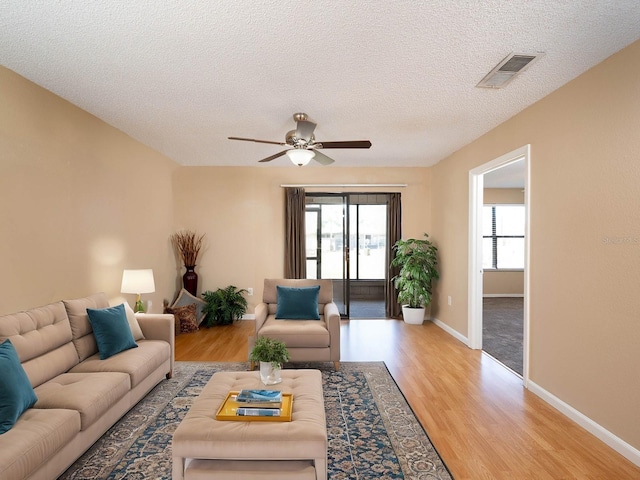 living room with a textured ceiling, light hardwood / wood-style floors, and ceiling fan