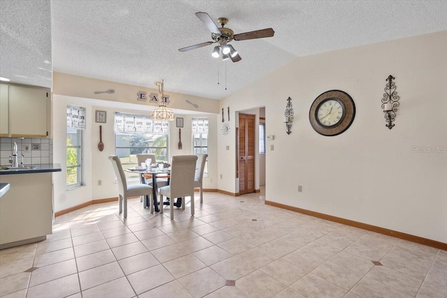 dining space featuring lofted ceiling, sink, light tile patterned floors, ceiling fan, and a textured ceiling