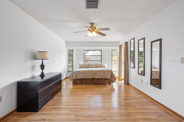 bedroom featuring ceiling fan, a textured ceiling, and light wood-type flooring