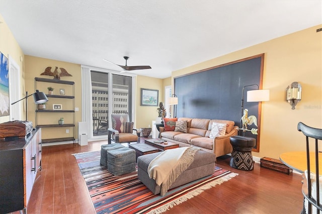 living room with dark wood-type flooring and ceiling fan