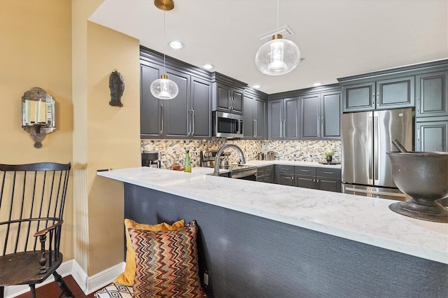 kitchen with hanging light fixtures, backsplash, stainless steel appliances, light stone counters, and kitchen peninsula