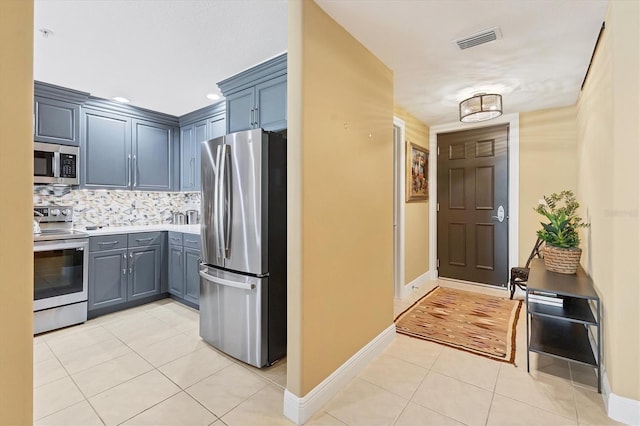 kitchen featuring blue cabinetry, stainless steel appliances, decorative backsplash, and light tile patterned floors