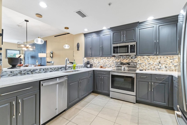 kitchen featuring sink, gray cabinetry, tasteful backsplash, appliances with stainless steel finishes, and pendant lighting