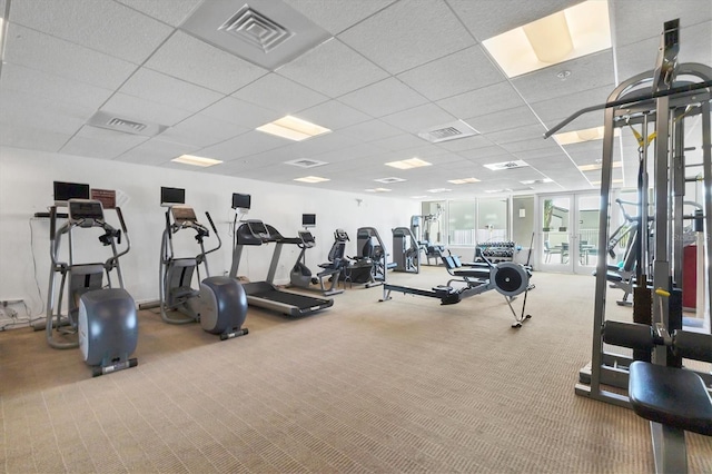 workout area with a paneled ceiling and light colored carpet