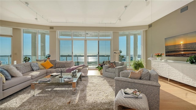 sunroom featuring rail lighting and a water view