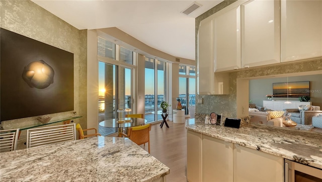 interior space with white cabinetry, decorative backsplash, light stone countertops, and wine cooler