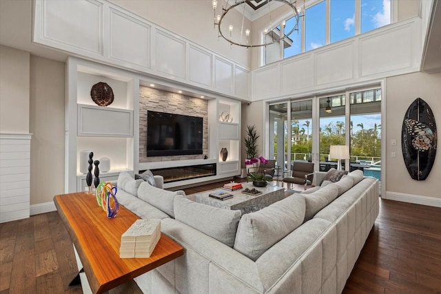 living room with a towering ceiling, a notable chandelier, and dark hardwood / wood-style flooring