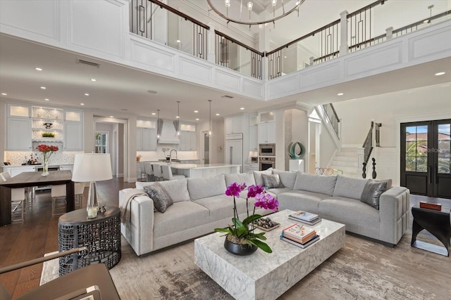 living room featuring sink, french doors, a high ceiling, and light hardwood / wood-style flooring